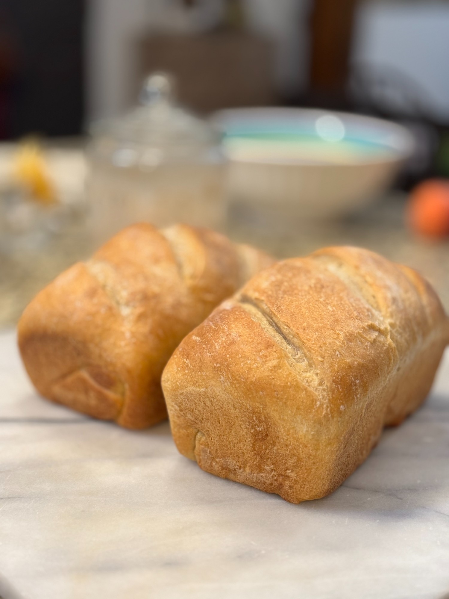 Two golden sourdough sandwich mini loaves on a marble surface